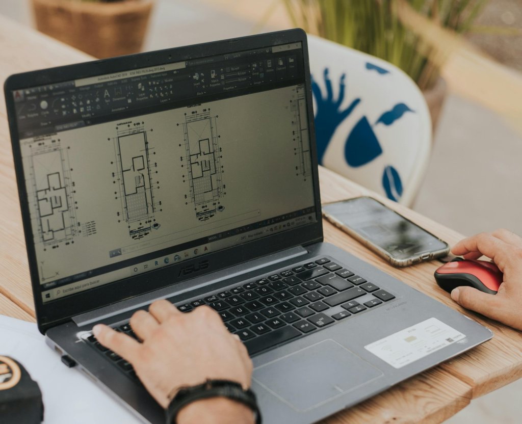 An architect working on building designs using a laptop outdoors, highlighting modern architecture.